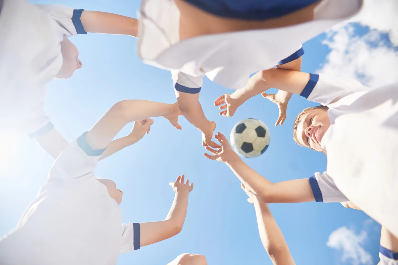 Young team reaching for soccer ball, showing teamwork in website design.
