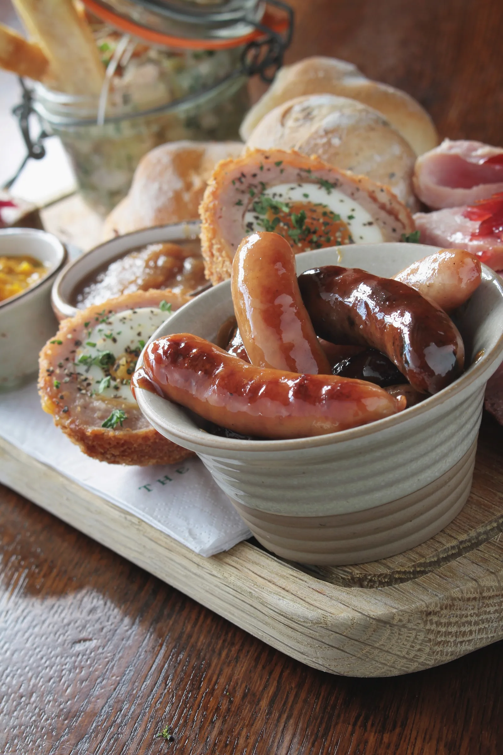 Gourmet platter with sausages, scotch eggs, and bread, for website design.