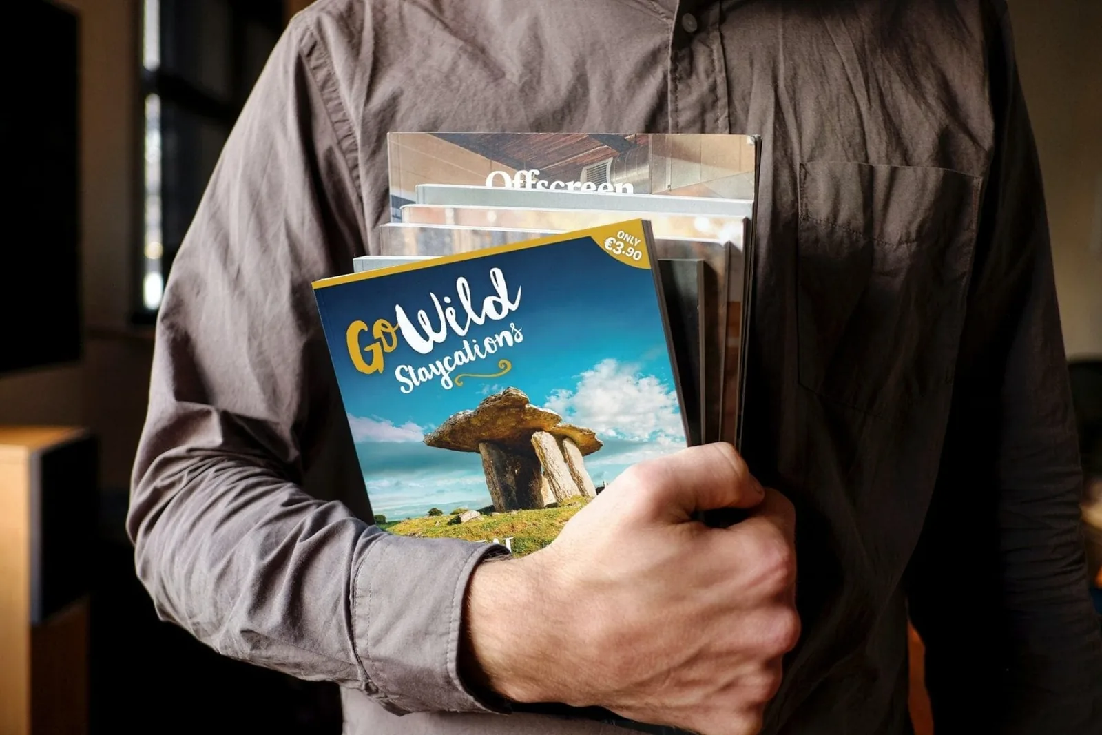 Person holding "GoWild Staycations" magazine, showcasing brand identity design.
