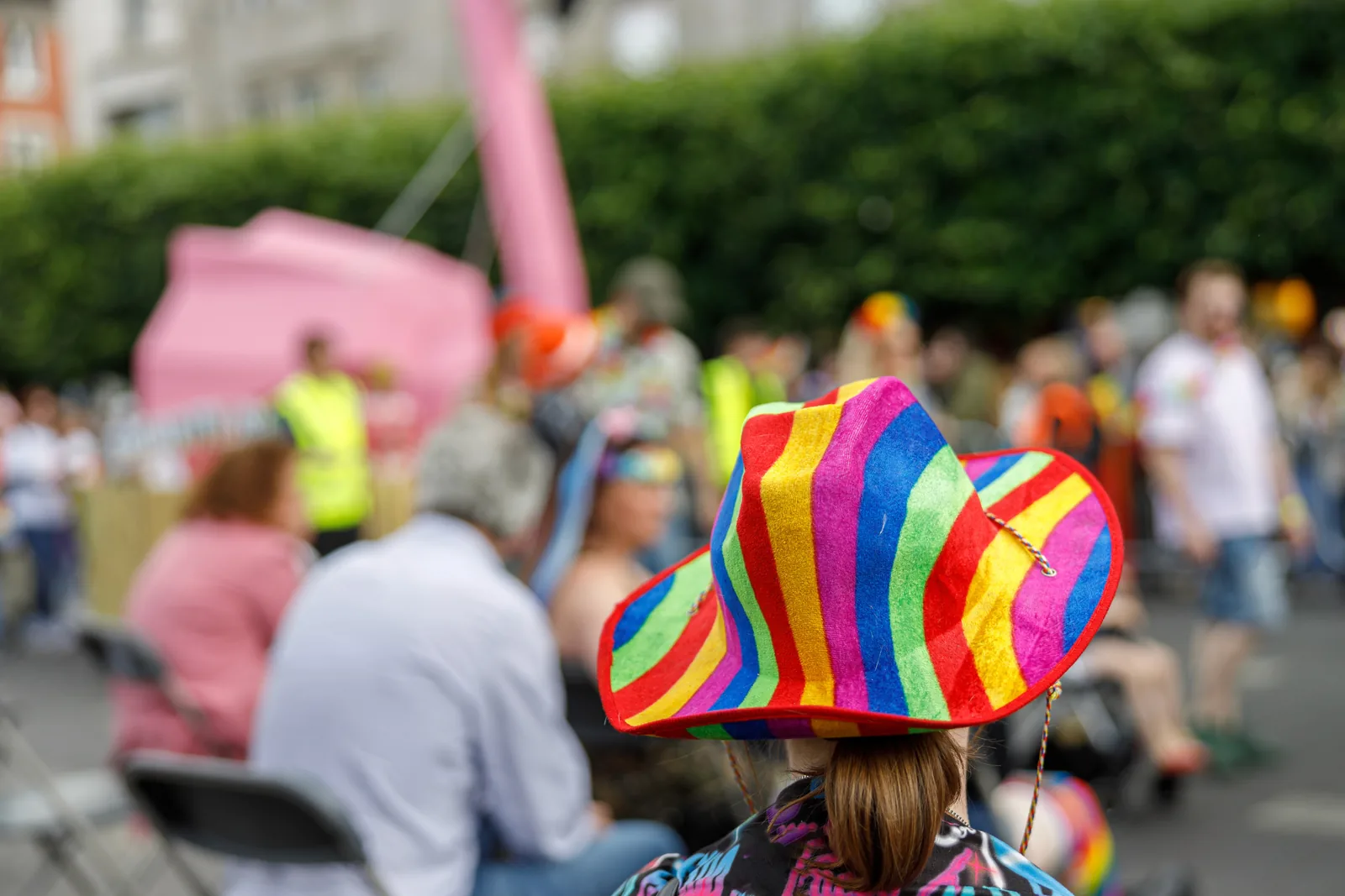 Rear view of person in rainbow hat at lively event, for website design.