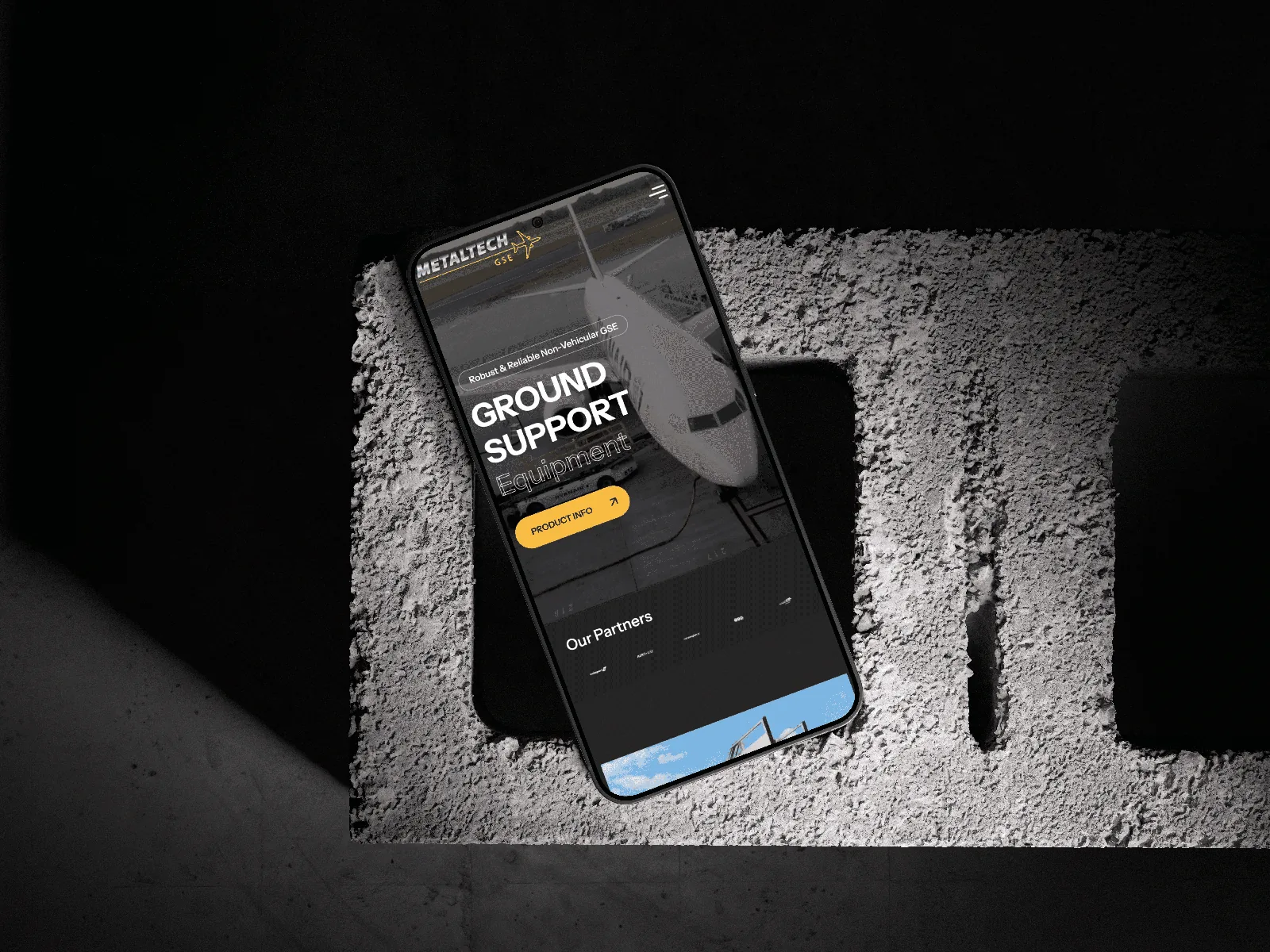Metaltech ground-support website displayed on a phone in a rugged black setting